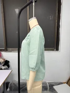 Green linen-blend short-sleeve top detail, featuring square collar and delicate lace patchwork.