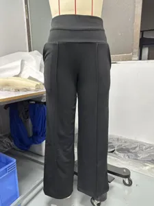 Dettaglio di pantaloni neri a vita alta ampi con cintura incrociata e piega centrale.