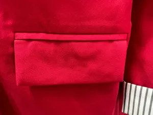 Close up detail of women red casual blazer featuring tailored flap pocket and striped cuff.