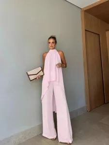 Vista dettagliata del top rosa elegante e dei pantaloni larghi indossati in un ambiente moderno.