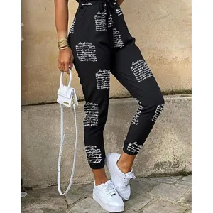 Schwarzer Utility Jumpsuit mit weißem Handschrift-Print, Taillengürtel und Saum Detail.