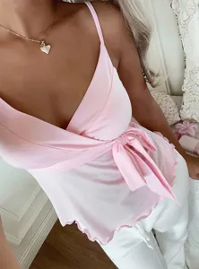 Close-up detail of the pink v-neck camisole, featuring stylish side bow and lettuce trim.