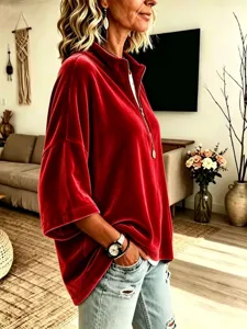 Primo piano del top in velluto rosso da donna che mostra la zip e il colletto alto morbido.