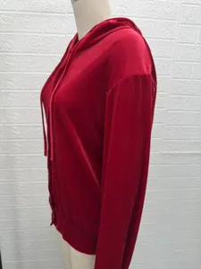Rote Samt Kapuzenstrickjacke Detail, weiche Stofftextur, lange Ärmel und Knopfverschluss.