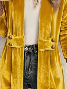Dettaglio in tessuto di velluto dorato, decorazione con bottoni, cardigan aperto, elegante.