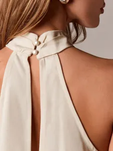 Rückseitenansicht des eleganten Satin-Haltertops mit Perlenknöpfen und ärmellosem Design.