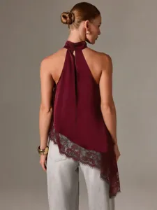 Detailansicht des eleganten burgunderroten Satinoberteils mit asymmetrischem Spitzen saum.