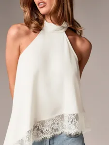 Detailansicht eines weißen Neckholder-Tops mit glattem Satin und feinem Spitzensaum.