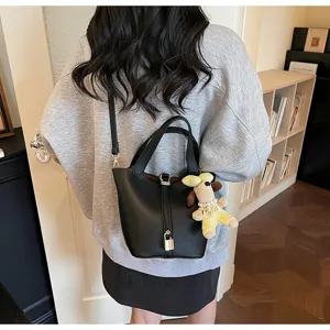 Black soft leather bucket bag detail showing metal padlock and cute puppy pendant.