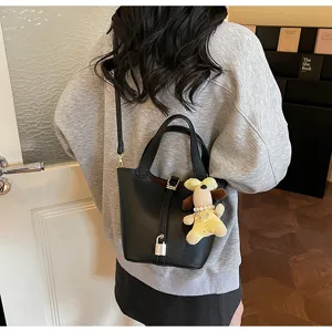 Stylish black leather bucket bag with lock detail and cute dog charm for daily commute.