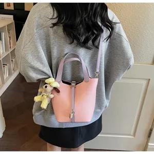 Sweet pink soft leather bucket bag with cute dog pendant, stylish and versatile shoulder bag.