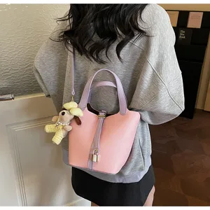 Chic pink soft leather bucket bag with purple handles and cute dog pendant for women.