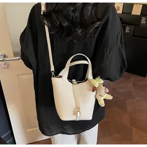 Chic minimalist bucket bag with top handle and cute puppy charm for daily casual commute style.