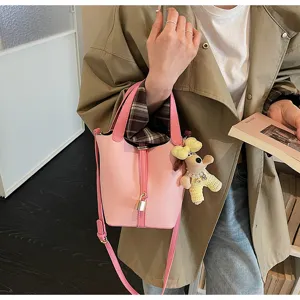 Pink soft leather bucket bag detail, chic commuter cross body bag with cute doll charm.