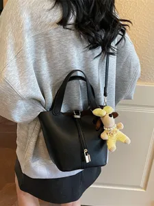 Black leather bucket bag for women, classic design shoulder handbag with dog charm.