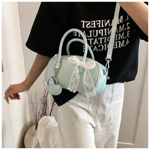 Detail view of light blue bowling handbag with white lace bow and heart charm accessory.