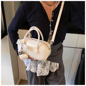 Close-up of the sweet white bowling handbag with delicate lace trim, heart charm, and strap.