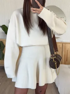 Elegant white knit two-piece set featuring long sleeve top and flared short skirt for women.