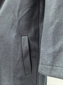 Close-up detail view of dark grey wool blend winter coat pocket and sleeve texture.