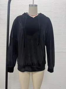 Detailed view of the black velvet hoodie showing soft texture, cozy hood and ribbed cuffs.