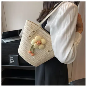 Detail view of women straw woven bucket bag with cute floral pendant for summer beach use.