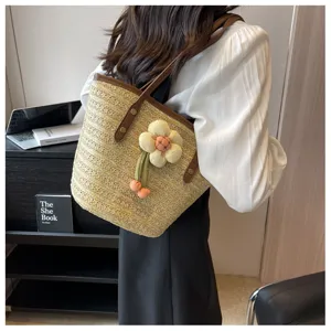 Straw woven bucket bag for women summer beach shoulder bag with cute flower pendant detail.