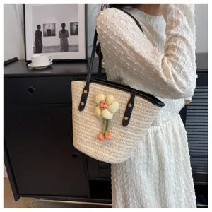 Woven straw bucket bag with black leather straps and cute fabric flower accent for summer.