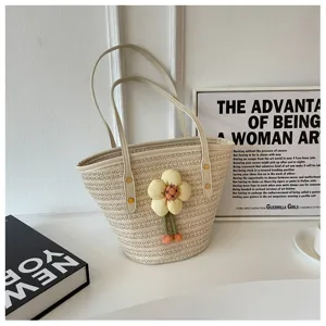 Detailed view of the woven straw bucket bag featuring a cute yellow fabric flower charm and leather handles.