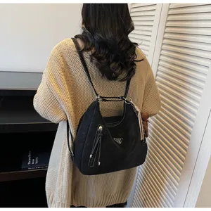 Detail shot of vintage black convertible backpack and shoulder bag with metal logo detail.
