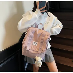 Detail shot of a casual pink nylon backpack with cute bear pendant and front label tag.