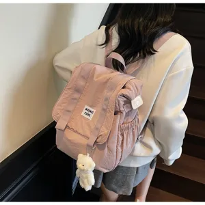 Detail view of the casual nylon backpack with cute bear pendant and stylish front label.