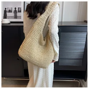 Dettaglio della borsa a spalla in paglia intrecciata, texture estiva e grande capacità.