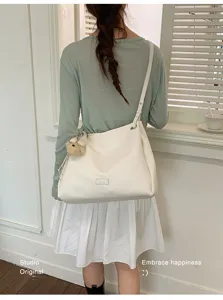 Vue détaillée du sac cabas d'épaule blanc élégant avec un adorable pendentif d'ours.