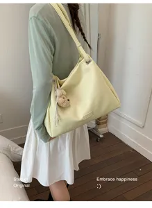 Vue détaillée du sac cabas souple pour femme en jaune avec charmant pendentif ours en peluche.