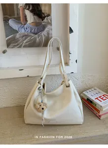Gros plan sur le sac cabas souple en cuir blanc avec un joli pendentif en peluche d'ours mignon.