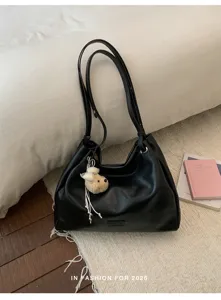 Détail du sac cabas d'épaule en cuir PU noir au design souple avec un charmant pendentif d'ours.