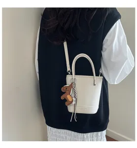 Women bucket shoulder bag in litchi pattern leather with cute horse charm for commuting daily wear.