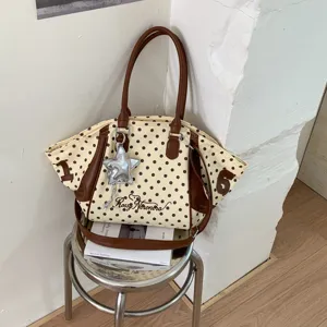 Detailed view of stylish polka dot tote bag with brown leather accents and star pendant.