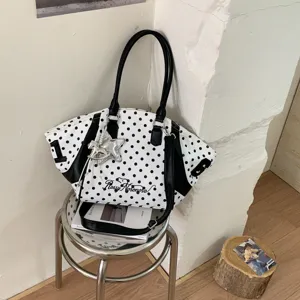 Detail shot of a black and white polka dot tote bag with metal star charm and side numbers.
