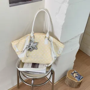 Detail view of a stylish yellow polka dot tote shoulder bag with white straps and star charm.