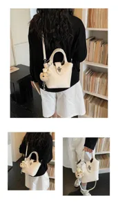 Detailed view of women white leather bucket bag with cute bear charm and metal lock.