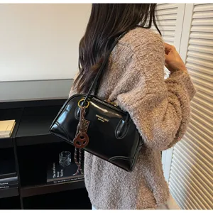 Classic black patent leather shoulder pillow bag for women, stylish vintage commute handbag.