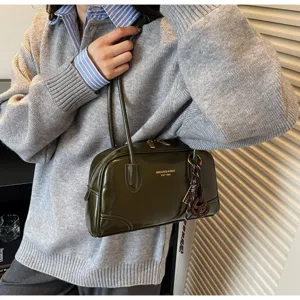Dark green patent leather shoulder bag, retro pillow bag style with handle and chic charm detail.