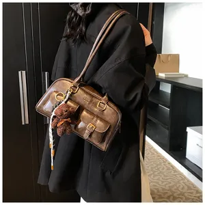 Detailansicht der vintage braunen Umhängetasche mit mehreren Taschen und Bärenanhänger.