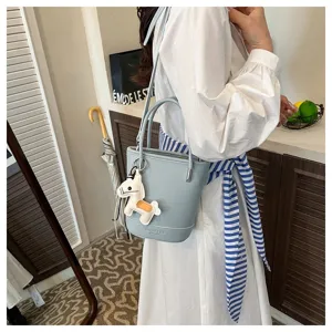 Light blue litchi pattern bucket bag detail shot with cute horse charm and shoulder strap.