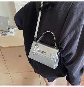 Silver metallic mini shoulder bag with top handle and cute bear charm for stylish women.