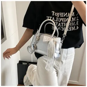 Silver metallic bowling bag detail, featuring white lace bow and heart pendant charm for women.