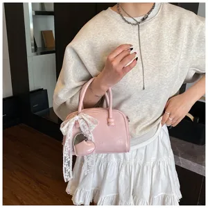 Women pink patent leather bowling handbag with cute white lace ribbon and heart charm.