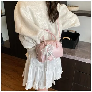 Detailed view of the pink bowling handbag featuring a delicate white lace bow and strap.