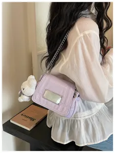 Detail view of light purple patent leather shoulder bag with chain strap and cute bear charm.